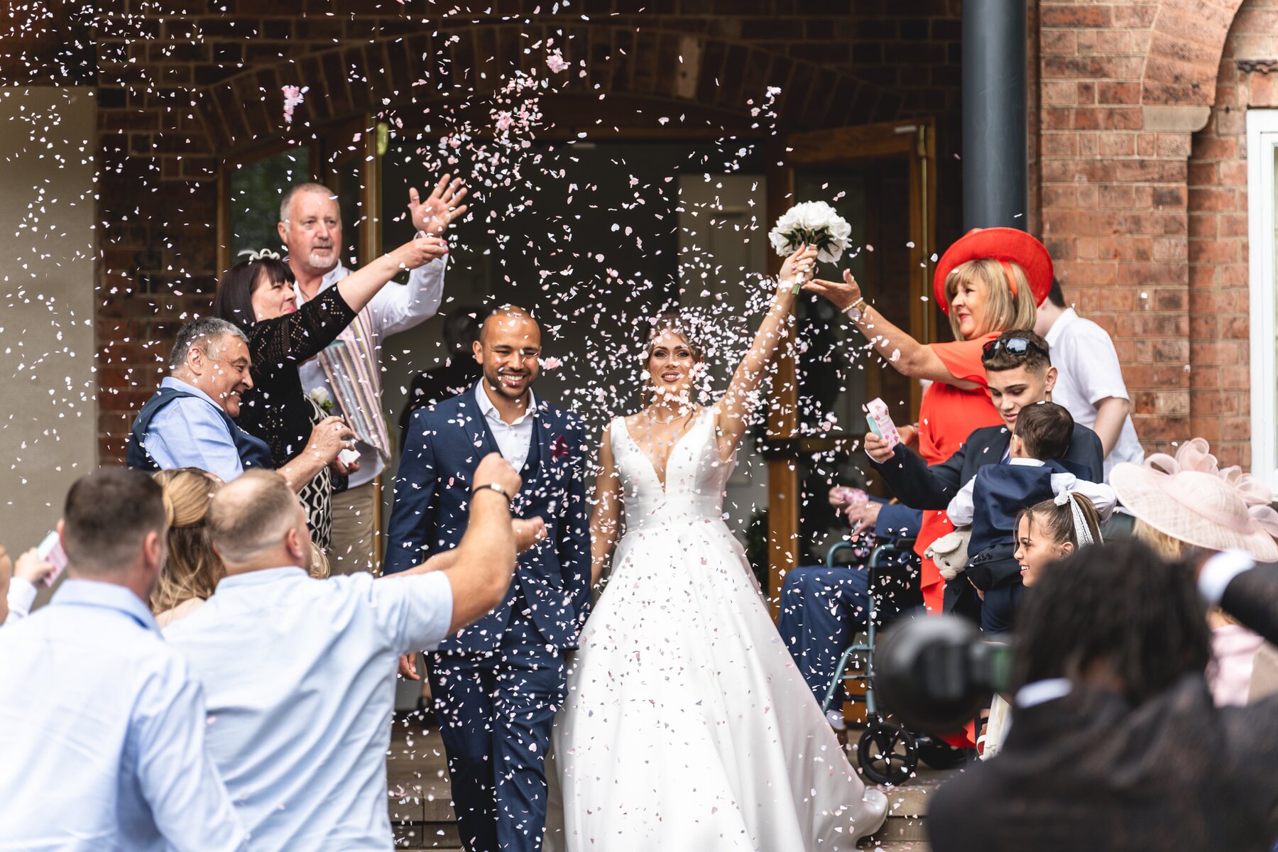 Newlyweds laughing as guests shower them with confetti