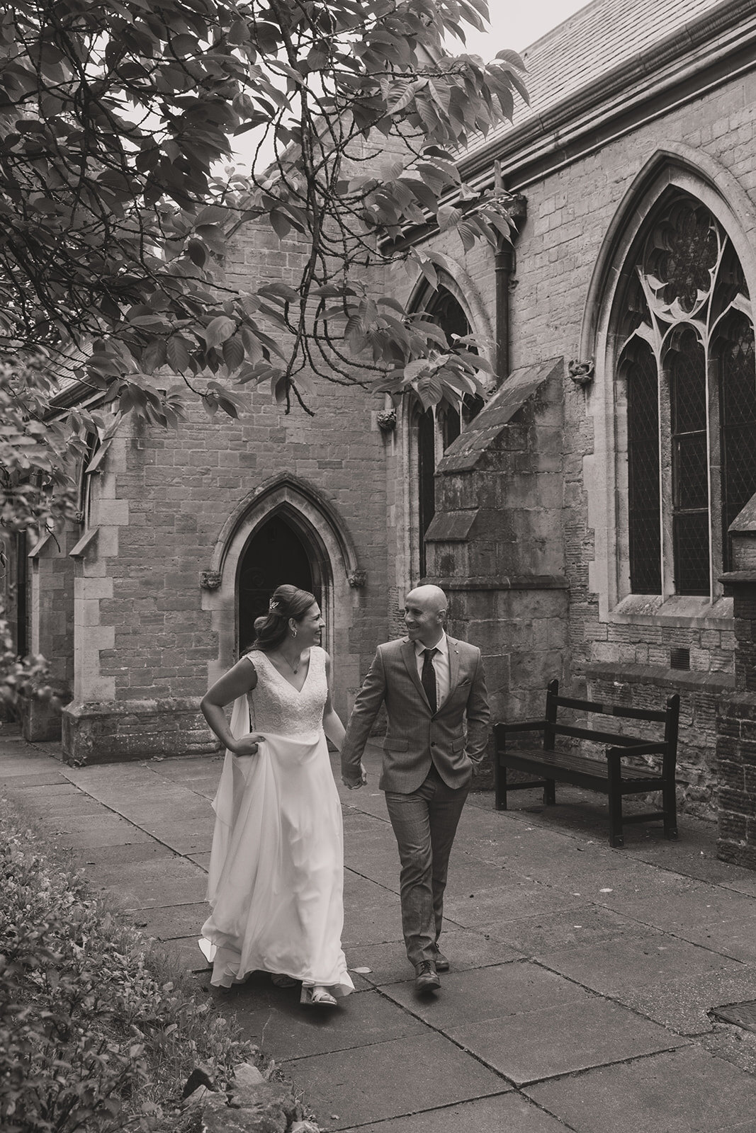 Black and white photograph of newlyweds walking beside their church